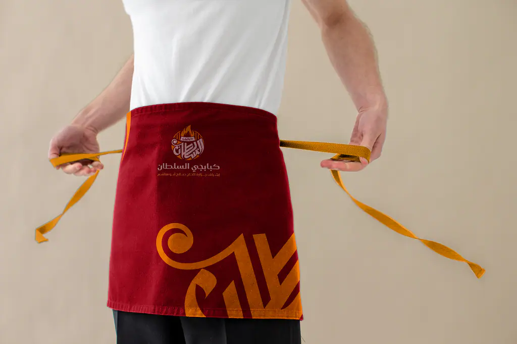 Kababgy Al-Sultan waist apron with the orange letter motif